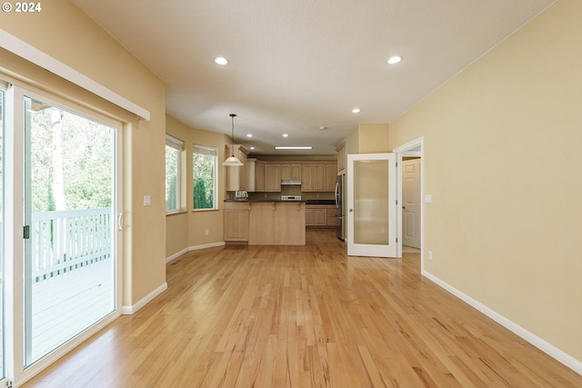 kitchen with hanging light fixtures, light hardwood / wood-style floors, light brown cabinets, and stainless steel fridge