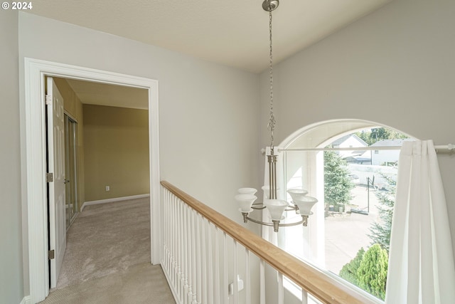 corridor featuring light colored carpet and a chandelier