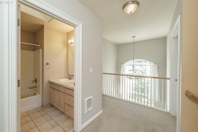 hall with light carpet, heating unit, an inviting chandelier, and sink