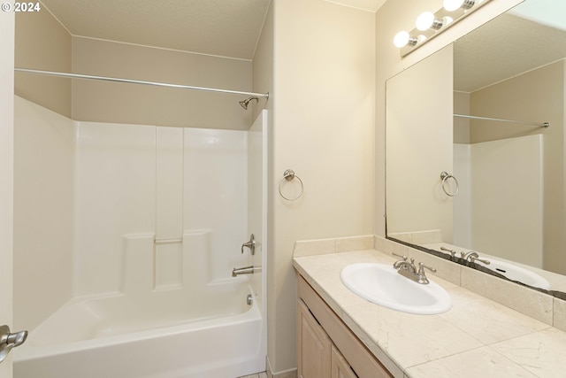 bathroom with a textured ceiling, washtub / shower combination, and vanity