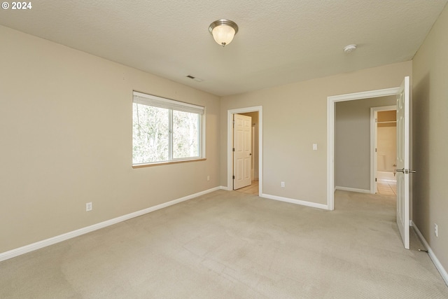 unfurnished bedroom featuring a textured ceiling and light colored carpet