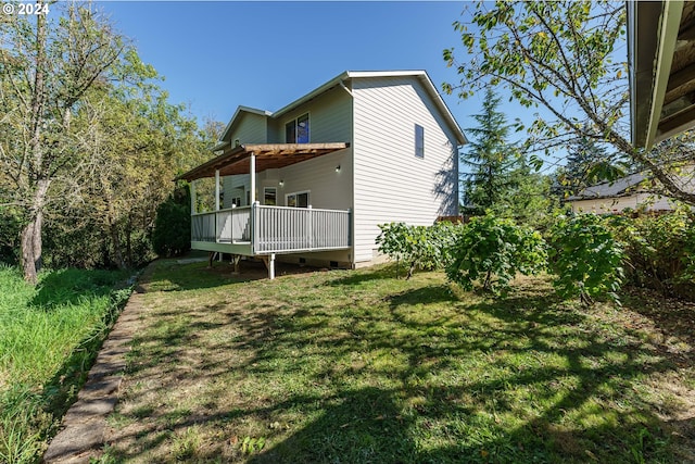 rear view of house featuring a lawn and a deck