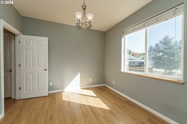 spare room featuring light hardwood / wood-style flooring and a notable chandelier