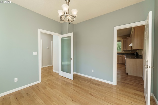 spare room with an inviting chandelier and light hardwood / wood-style floors