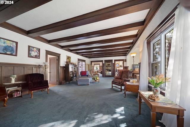 living area featuring beamed ceiling and carpet floors