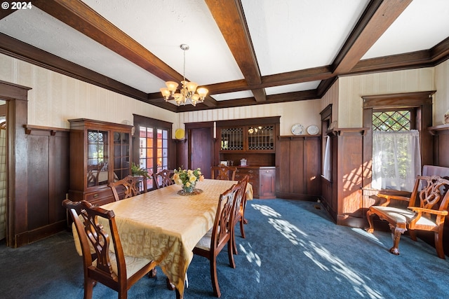 dining room with beamed ceiling, a healthy amount of sunlight, and dark colored carpet