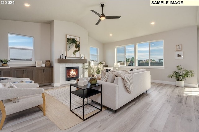 living room with ceiling fan, light hardwood / wood-style floors, and vaulted ceiling