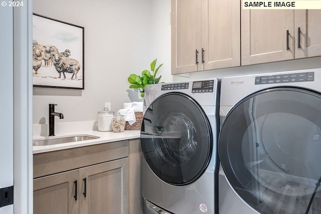 laundry room featuring washing machine and clothes dryer, sink, and cabinets