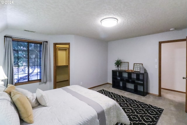 carpeted bedroom with a textured ceiling and vaulted ceiling