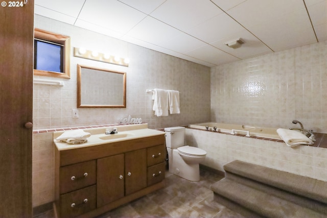 bathroom featuring vanity, a relaxing tiled tub, toilet, and tile walls