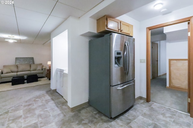 kitchen with stainless steel fridge with ice dispenser, light brown cabinets, washer / clothes dryer, and light colored carpet