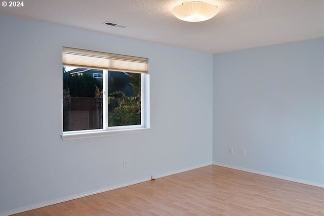 empty room featuring a textured ceiling and light hardwood / wood-style floors