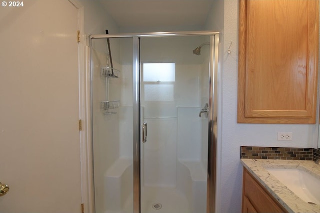 bathroom with vanity, backsplash, and walk in shower