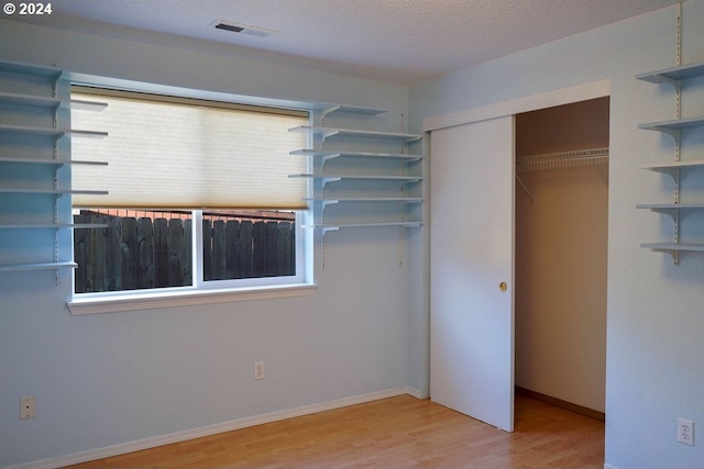 unfurnished bedroom featuring a closet, a textured ceiling, and hardwood / wood-style floors