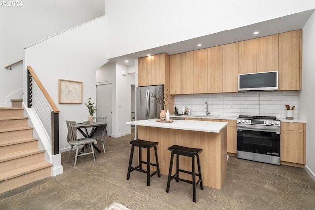 kitchen featuring backsplash, appliances with stainless steel finishes, sink, a towering ceiling, and a center island