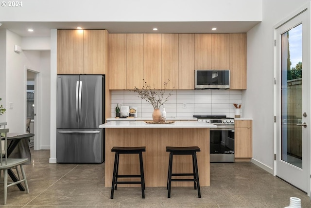 kitchen featuring a kitchen island, backsplash, a breakfast bar, light brown cabinetry, and appliances with stainless steel finishes