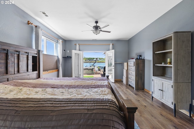 bedroom featuring ceiling fan, a water view, and light hardwood / wood-style flooring