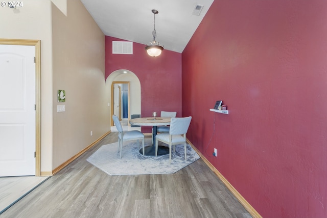 dining area with high vaulted ceiling and light hardwood / wood-style flooring