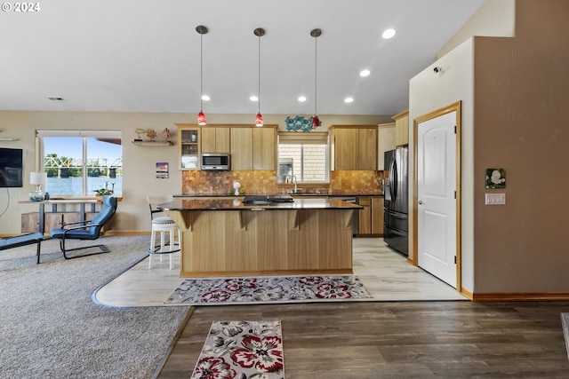 kitchen with a center island, light hardwood / wood-style flooring, a breakfast bar area, appliances with stainless steel finishes, and decorative light fixtures