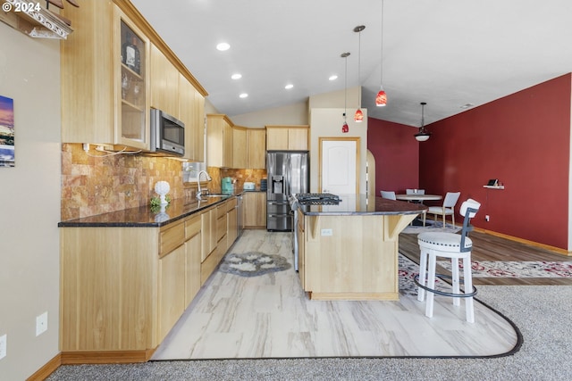 kitchen featuring vaulted ceiling, tasteful backsplash, a kitchen island, appliances with stainless steel finishes, and light brown cabinetry