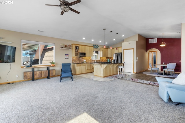 carpeted living room featuring ceiling fan and vaulted ceiling