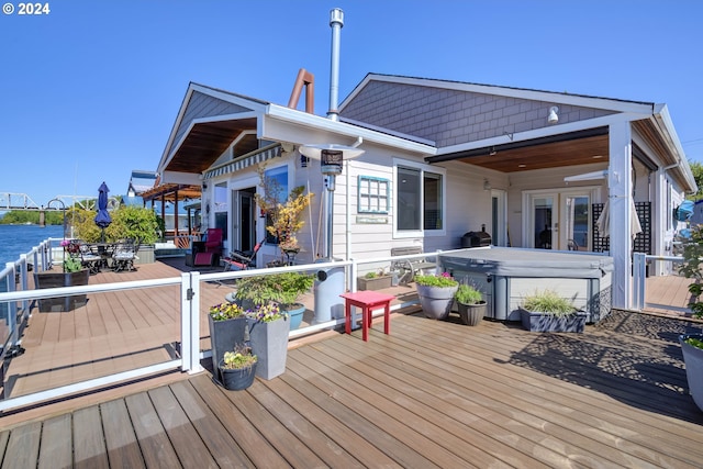 wooden terrace featuring a hot tub, a water view, and ceiling fan