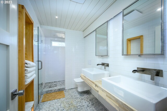 bathroom with toilet, sink, tile walls, and walk in shower