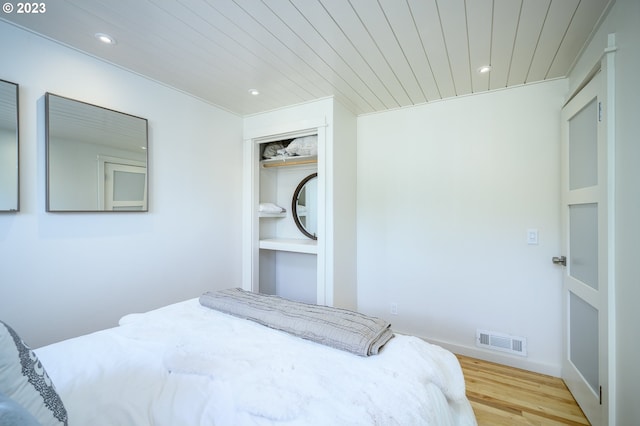 bedroom with a closet, wooden ceiling, and light wood-type flooring