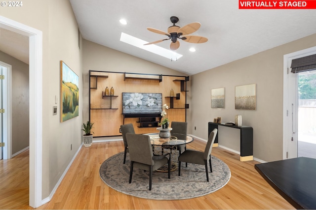 dining space featuring ceiling fan, light hardwood / wood-style flooring, and lofted ceiling with skylight