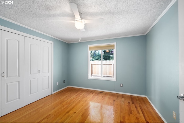 unfurnished bedroom featuring ceiling fan, a closet, ornamental molding, and hardwood / wood-style flooring