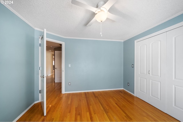 unfurnished bedroom featuring crown molding, light hardwood / wood-style flooring, ceiling fan, a textured ceiling, and a closet