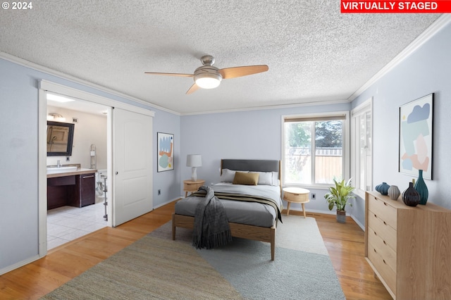 bedroom featuring ensuite bathroom, crown molding, ceiling fan, and light wood-type flooring