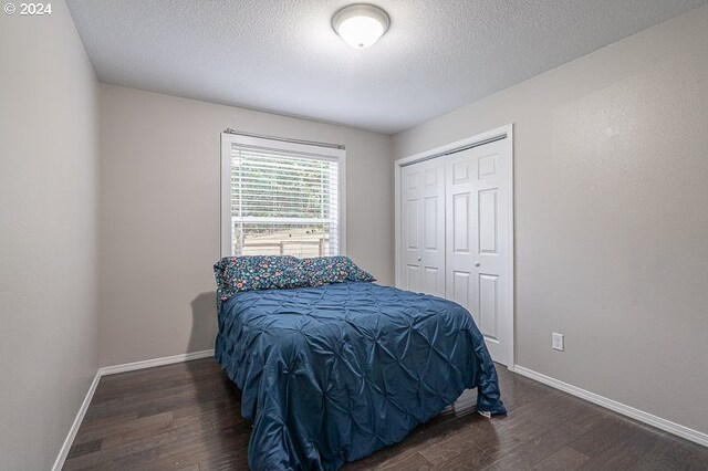 bedroom featuring a closet, dark hardwood / wood-style floors, and a textured ceiling