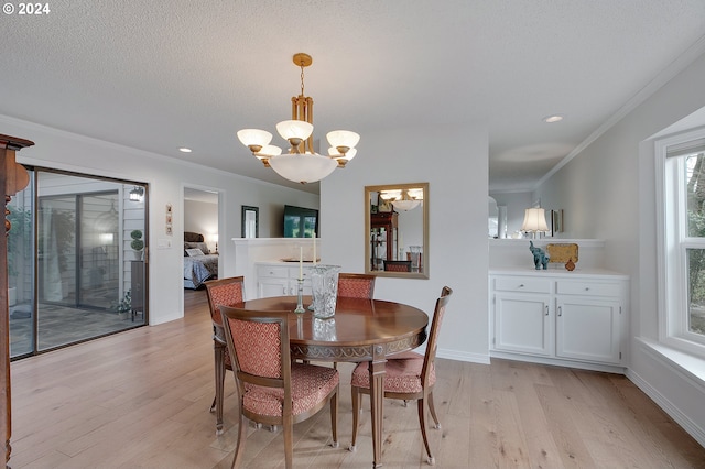 dining room with ornamental molding, a notable chandelier, a textured ceiling, and light wood-type flooring