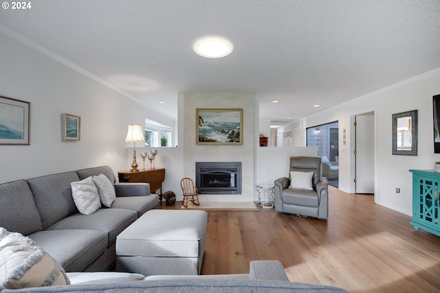 living room featuring a large fireplace, crown molding, a textured ceiling, and light wood-type flooring