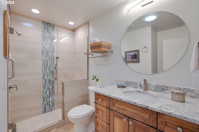 bathroom featuring vanity, a shower with shower door, and toilet