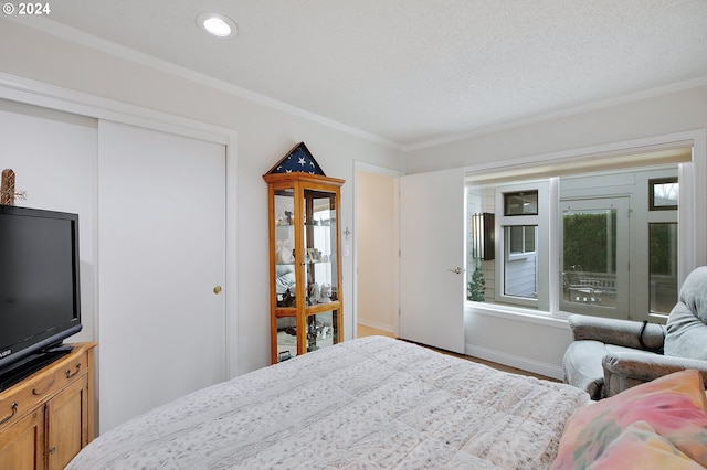 bedroom with a closet, crown molding, and a textured ceiling