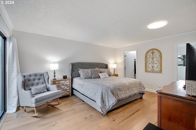 bedroom featuring light hardwood / wood-style floors, a textured ceiling, and ornamental molding