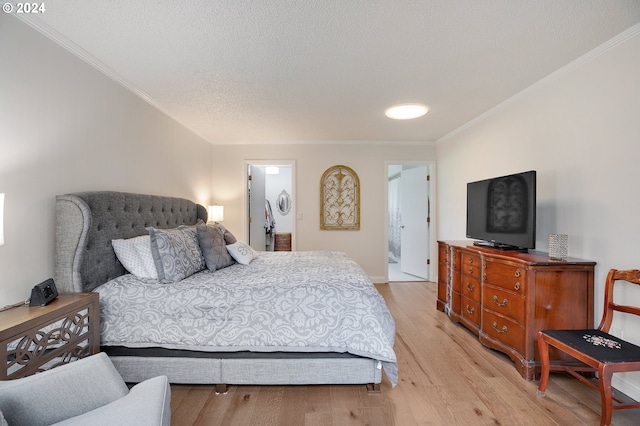 bedroom featuring ornamental molding, a textured ceiling, light hardwood / wood-style floors, and ensuite bath