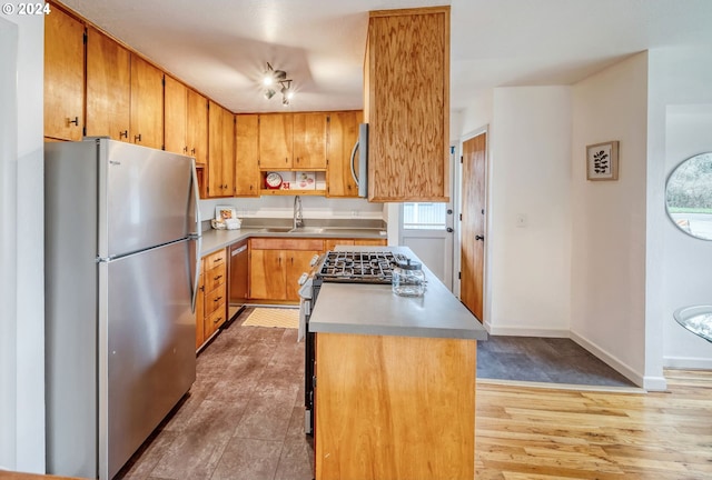 kitchen featuring appliances with stainless steel finishes, sink, a kitchen island, and light wood-type flooring