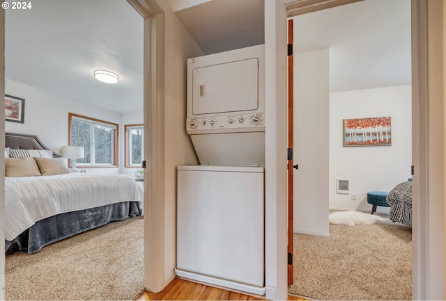 carpeted bedroom featuring stacked washer / dryer