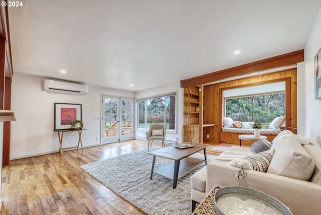 living room featuring light hardwood / wood-style flooring, an AC wall unit, a textured ceiling, and french doors