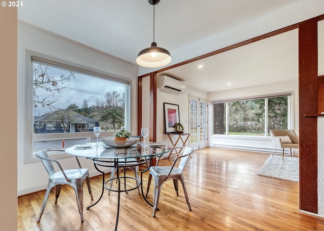 dining room featuring baseboard heating, a wall mounted AC, and light hardwood / wood-style flooring