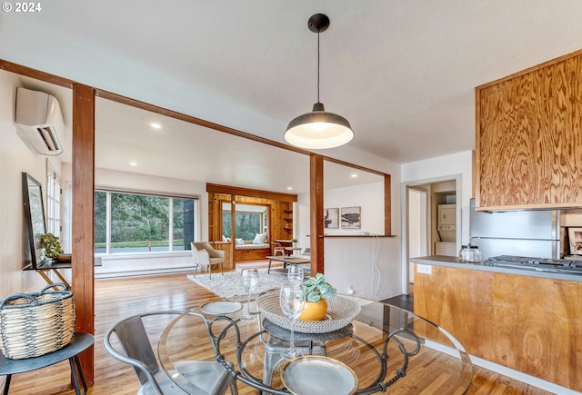 dining room with a wall mounted AC and light hardwood / wood-style floors