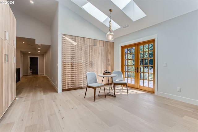 unfurnished room with a skylight, light wood-type flooring, high vaulted ceiling, and french doors