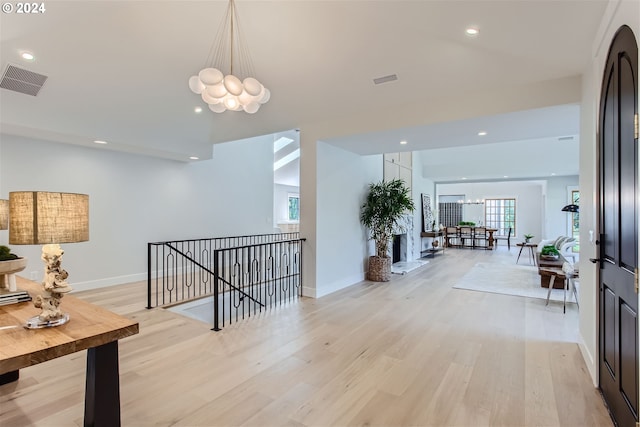 hall featuring light wood-type flooring and a chandelier