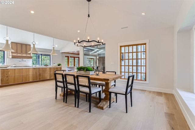 dining space with vaulted ceiling, light wood-type flooring, and an inviting chandelier