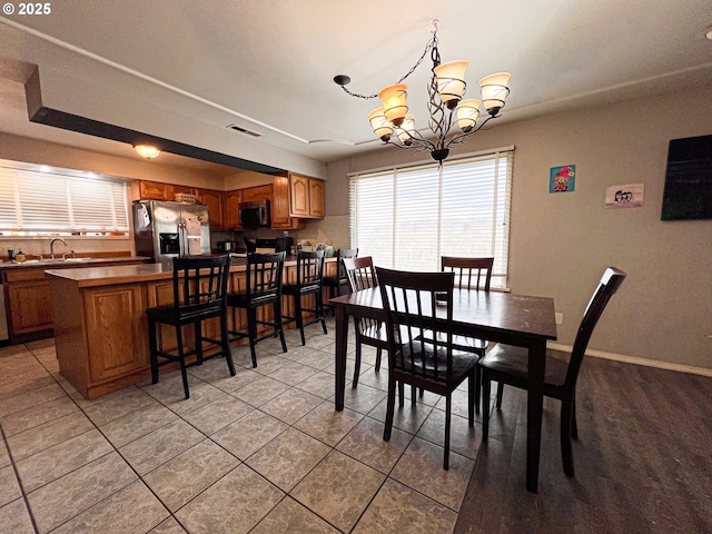 dining space featuring sink, light tile patterned flooring, and an inviting chandelier