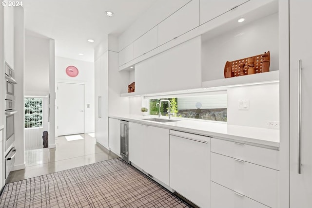 kitchen with white cabinets, white dishwasher, sink, and stainless steel oven