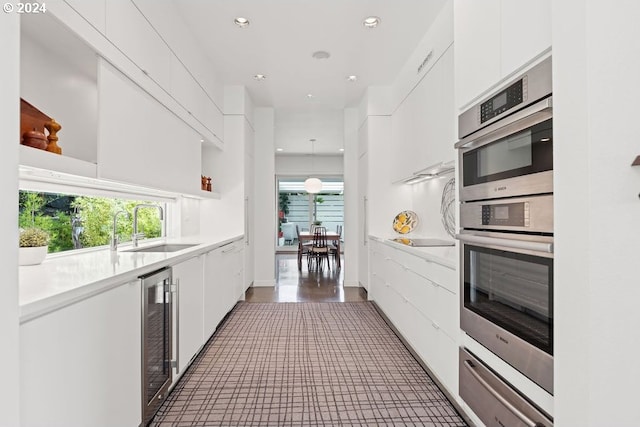 kitchen with dark hardwood / wood-style flooring, white cabinets, sink, decorative light fixtures, and wine cooler